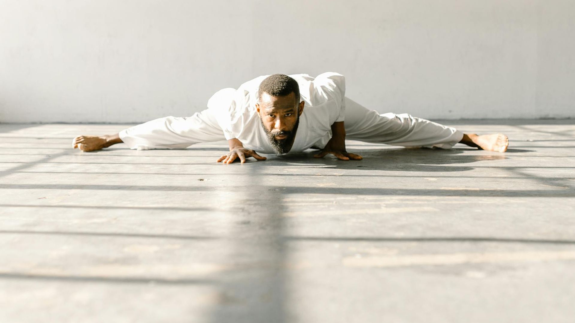 Silhouette of a man stretching in a calm, minimalist room.
